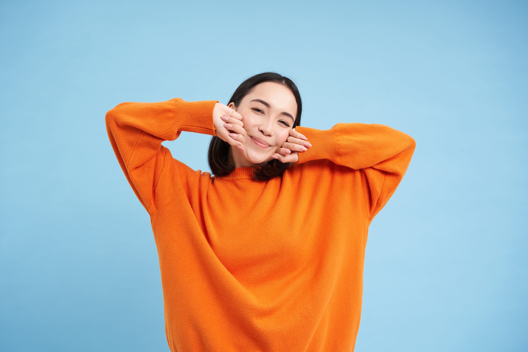 Elyxa Australian Organic Whole-food Supplements Smiling Young Korean Woman Stretching Her Arms With Satisfied Face, Pleased After Good Nap, Waking Up, Standing Over Blue Background