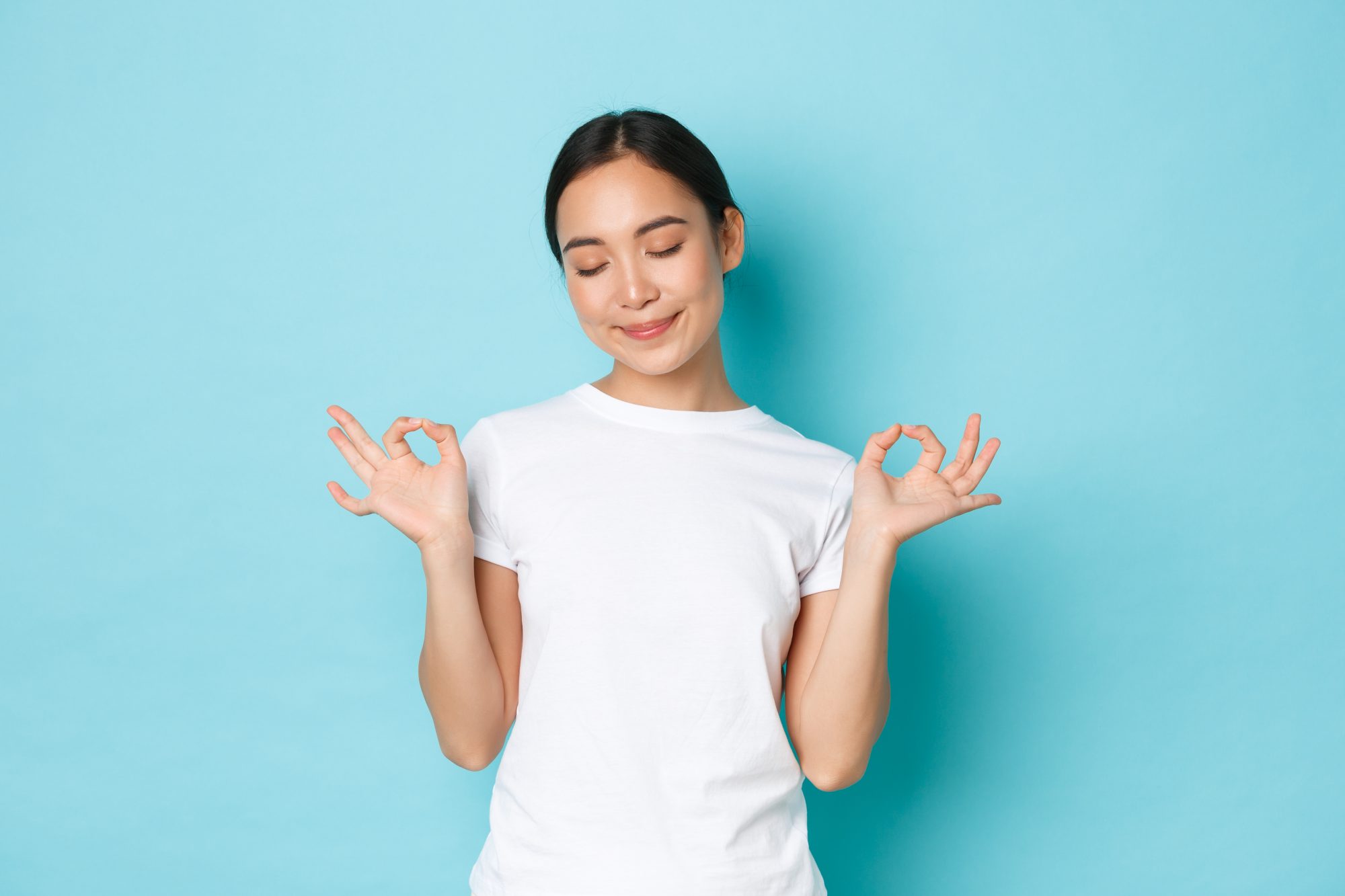 Elyxa Australian Organic Whole-food Supplements Patience Is Key. Calm And Relaxed Smiling Asian Girl With Closed Eyes And Lotus Pose, Standing Over Blue Background, Meditating Or Release Stress, Looking Peaceful And Happy
